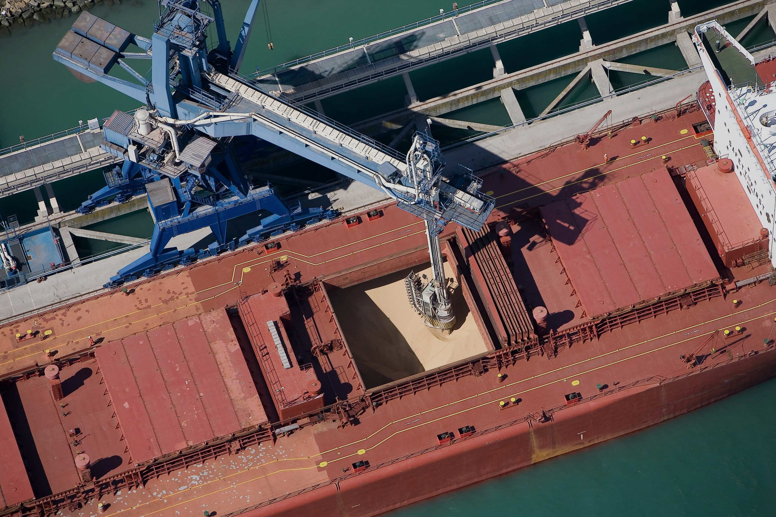 A dry-bulk carrier loading beneath a terminal shiploader.